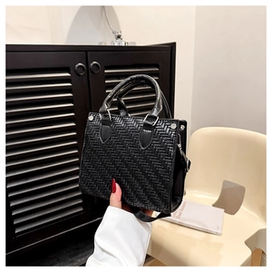Detailed view of black woven leather tote bag with intricate textured lattice pattern