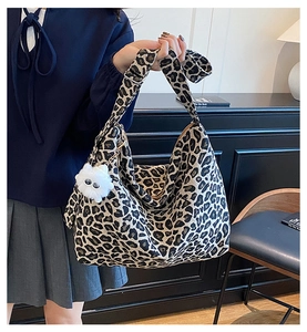 Close-up of leopard print canvas tote bag featuring a white plush pom-pom charm