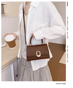 Detail of brown crocodile pattern shoulder bag with golden buckle and sleek handle