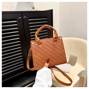 Detail of brown woven faux leather texture on tote bag with silver metal buckles