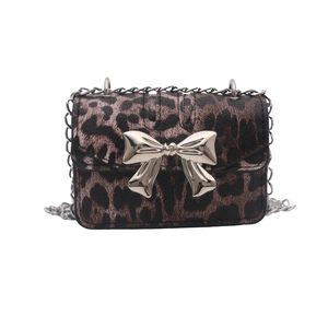 Leopard print crossbody bag with silver metal bow and chain strap on white background