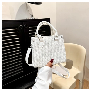 Detail view of a white woven tote bag featuring V-shaped texture and a detachable strap
