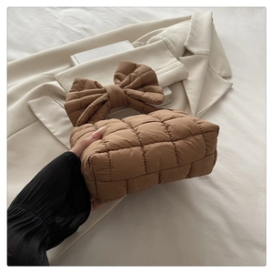 Dettaglio di una borsa imbottita trapuntata marrone con un grande fiocco sul manico