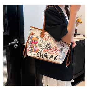 Fashionable graffiti tote bag with colorful bear prints and brown leather straps worn by model