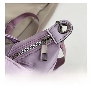 Macro detail of the smooth metal zipper and nylon fabric texture of the purple hobo bag