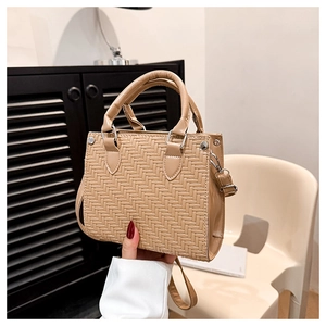 Close-up of the textured woven leather pattern and metal rivets on the tote bag
