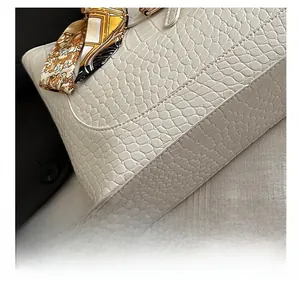 Close-up of crocodile-embossed leather tote bag with precise stitching and silk scarf decoration