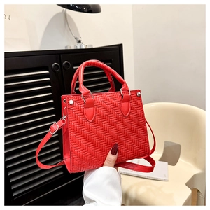 Detailed view of red woven texture on tote bag with silver hardware and shoulder strap