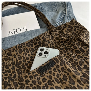 Detail of leopard print canvas tote bag featuring an outer pocket and interior storage