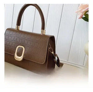Detail of brown crocodile embossed bag showing gold hardware hooks and texture