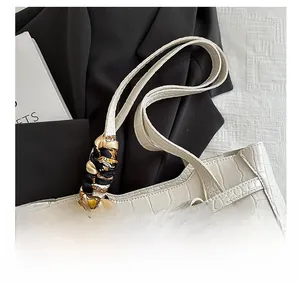 Detail of white crocodile pattern tote bag with decorative printed silk scarf on handle