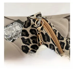 Detail of leopard print fabric bag showing smooth metal zipper and white plush charm