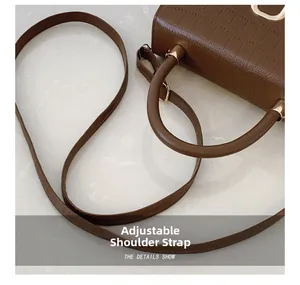 Detail showing the adjustable shoulder strap and crocodile embossed leather on the bag