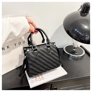 Detailed view of black woven leather tote bag with circular handles and silver D-ring