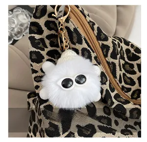 Detail of white fluffy keychain with sunglasses decor on a leopard print handbag