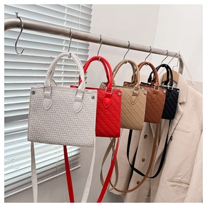 Close-up of woven texture tote bags in five colors hanging on a display rack