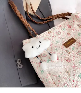 Detail of printed tote bag with floral patterns and plush charm on a grey blazer
