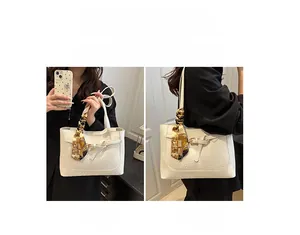 Detail showing white tote bag with crocodile texture used as shoulder and handbag
