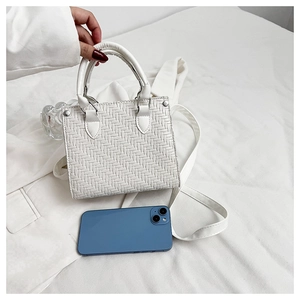 Detailed top view of white woven texture tote bag with blue phone for size comparison