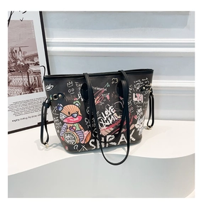 Close-up of black graffiti tote bag with colorful cartoon bear and artistic heart prints