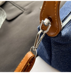 Detail of blue denim and brown leather trim with silver rotating metal clasp