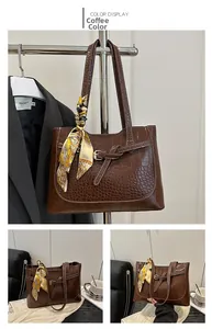 Detail of coffee tote bag with crocodile texture, metal buckle, and silk scarf handle