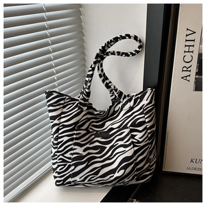 Close-up of zebra print canvas tote bag with outer pocket and brand label details