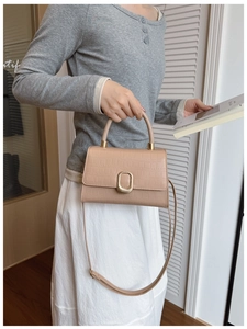 Detailed view of crocodile embossed leather texture and gold lock on beige handbag