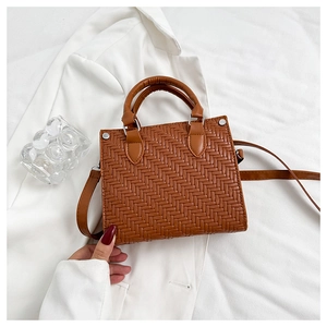 Close-up of woven PU leather texture and silver rivets on a brown vintage tote bag