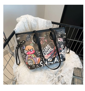 Detailed view of black graffiti tote bag with colorful cartoon patterns in a stylish setting