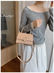 Model holding a beige crocodile pattern small square bag with golden clasp hardware