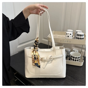 Detail of white crocodile pattern tote bag featuring a printed silk scarf on the handle