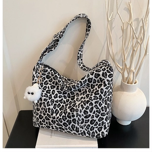 Close-up of leopard print tote bag with white plush charm on a decorative display
