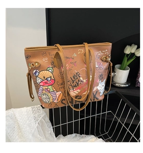 Detailed view of the brown leather tote bag with colorful bear graffiti and lace backdrop