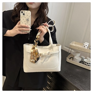 Detail of white crocodile pattern tote bag with decorative silk scarf and front buckle