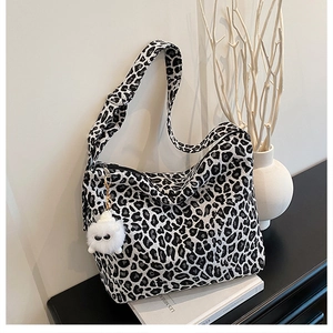 Close-up of leopard print canvas tote bag with soft plush monster charm and wide strap