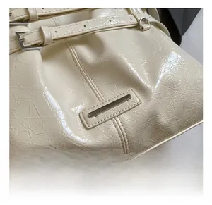 Detail of creamy off-white wrinkled patent leather texture and silver buckle on bucket bag