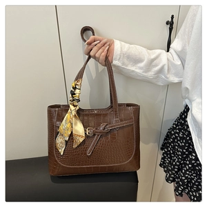 Detail of brown crocodile embossed tote bag with floral scarf handle and gold buckle
