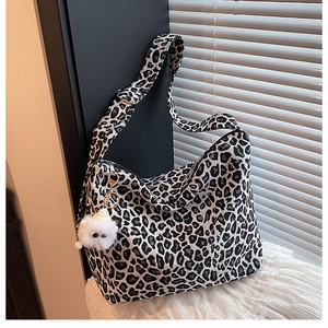 Detail of leopard print canvas tote bag with a cute white plush monster keychain charm