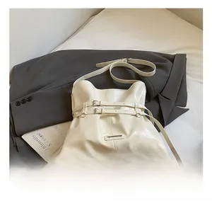 Close-up of beige leather tote with dual buckle details and metal brand plate