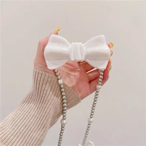 Coque iPhone avec nœud blanc pailleté et bandoulière en perles, présentation à la main