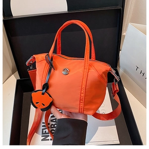 Placing a vibrant orange nylon dumpling bag with panda charm into a gift box