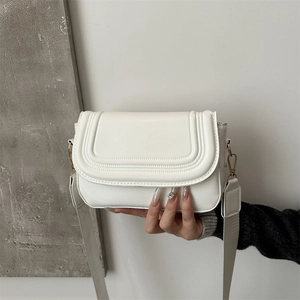 Borsa a tracolla minimalista in pelle bianca con patta a U e tracolla larga in mano