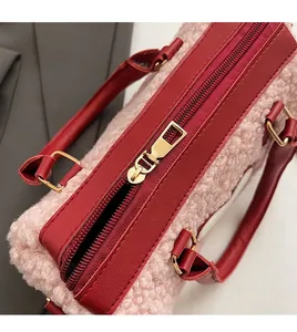 Detailed macro view of smooth gold zipper and red leather trim on pink faux fur handbag