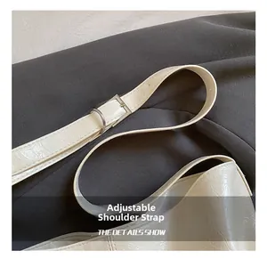 Detail of adjustable shoulder strap with silver buckle on cream gathered leather bucket bag