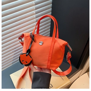 Detail of vibrant orange nylon handbag featuring M Fashion logo and cartoon panda charm