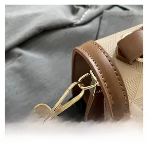Detail of geometric embossed texture and gold metal buckle on beige contrast handbag