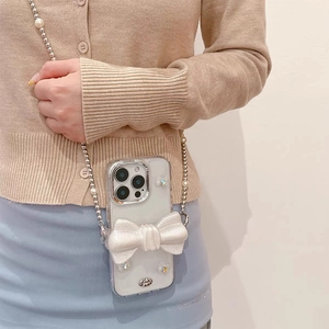 Vue détaillée de la coque iPhone à nœud scintillant 3D avec bandoulière perle et argent