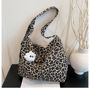 Detailed shot of leopard print canvas crossbody bag featuring a plush white charm