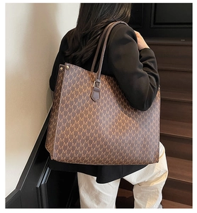 Macro shot of brown faux leather tote bag with classic M-letter pattern and riveted handles